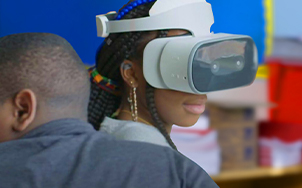 A student in a classroom uses a Lenovo Mirage VR headset