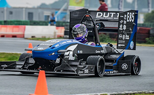 A blue and black formula race car being driven on a race track